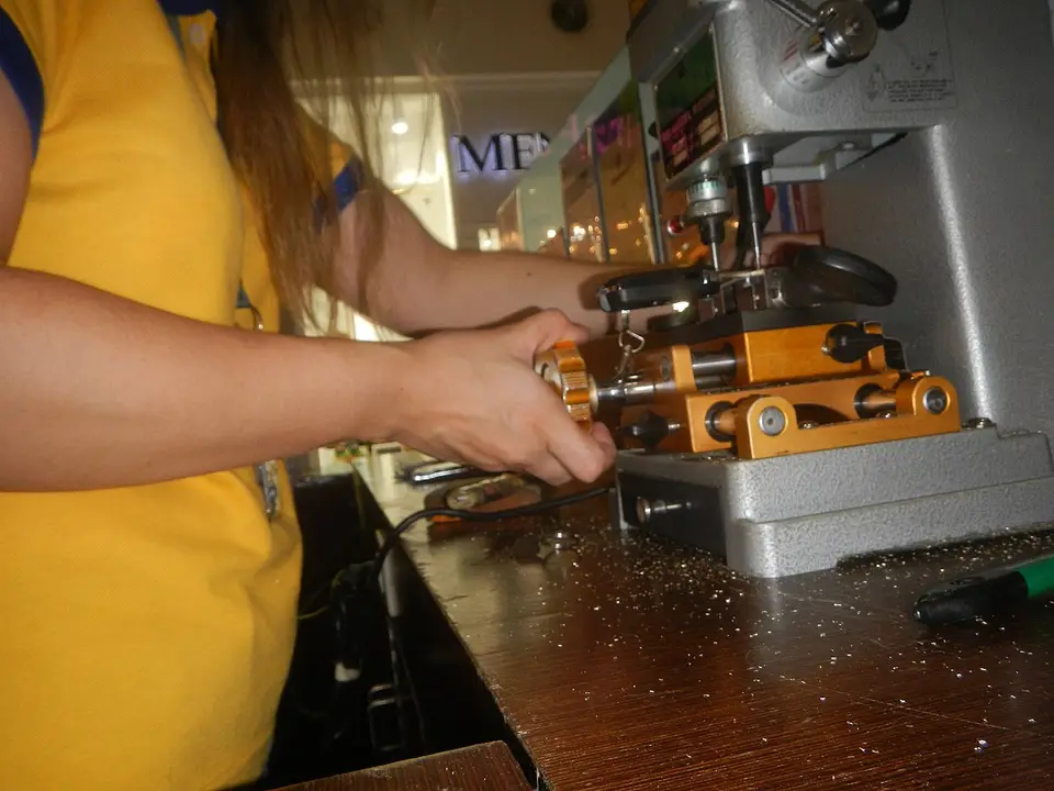 Manos copiando una llave en una máquina duplicadora