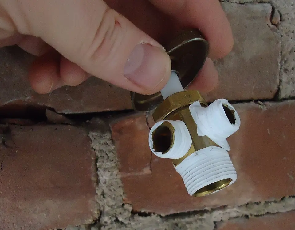 Mano enroscando una llave de paso con cinta de teflón